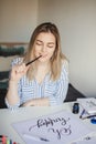 Young beautiful lady sitting at white desk and think about calligraphy Royalty Free Stock Photo