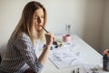 Young beautiful lady sitting at white desk and think about calligraphy Royalty Free Stock Photo