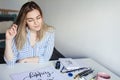 Young beautiful lady sitting at white desk and think about calligraphy Royalty Free Stock Photo