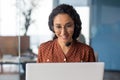 Young beautiful latin american woman with headset phone talking on video call using laptop, business woman inside office Royalty Free Stock Photo