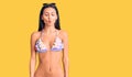 Young beautiful latin girl wearing bikini and sunglasses making fish face with lips, crazy and comical gesture