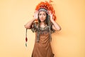 Young beautiful latin girl wearing indian costume trying to hear both hands on ear gesture, curious for gossip