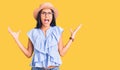 Young beautiful latin girl wearing summer hat and glasses crazy and mad shouting and yelling with aggressive expression and arms Royalty Free Stock Photo