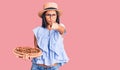 Young beautiful latin girl wearing summer hat and glasses holding pizza pointing with finger to the camera and to you, confident Royalty Free Stock Photo