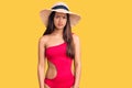 Young beautiful latin girl wearing swimwear and summer hat skeptic and nervous, frowning upset because of problem