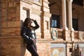 Young, beautiful, Latin and South American woman with leather top and jacket, sunglasses and jeans, leaning against a brick wall, Royalty Free Stock Photo