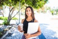 Young beautiful latin student with laptop and cup of coffee studying in the park. Girl is walking in the park with great smile and