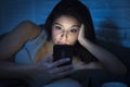 Young beautiful Latin woman on bed late at night texting using mobile phone sleepy and tired