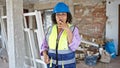 Young beautiful latin woman builder smoking cigarette with serious face at construction site Royalty Free Stock Photo