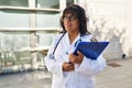 Young beautiful latin woman doctor smiling confident holding clipboard at hospital Royalty Free Stock Photo