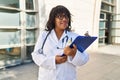 Young beautiful latin woman doctor smiling confident holding clipboard at hospital Royalty Free Stock Photo
