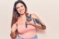 Young beautiful latin woman holding cat smiling happy pointing with hand and finger