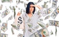 Young beautiful latin woman holding money bag with dollar symbol stressed and frustrated with hand on head, surprised and angry Royalty Free Stock Photo