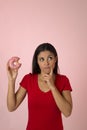 Young beautiful latin woman in red with pink sugar donut thinking and feeling guilty after biting Royalty Free Stock Photo