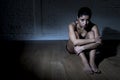 Young beautiful Latin woman or teen girl sitting sad and alone in edgy darkness feeling depressed Royalty Free Stock Photo