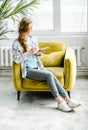 Young beautiful long haired college student girl in casual shirt with notebook,organizer pen sitting on yellow chair Royalty Free Stock Photo