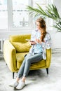 Young beautiful long haired college student girl in casual shirt with notebook,organizer pen sitting on yellow chair Royalty Free Stock Photo