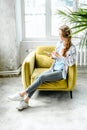 Young beautiful long haired college student girl in casual shirt with notebook,organizer pen sitting on yellow chair Royalty Free Stock Photo