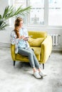 Young beautiful long haired college student girl in casual shirt with notebook,organizer pen sitting on yellow chair Royalty Free Stock Photo