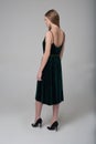 Young beautiful long-haired girl walks away in dark green dress