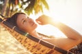 Young beautiful longhaired woman relaxing in hammock under the palm trees on the sandy Thailand beach. Exotic warm countries Royalty Free Stock Photo