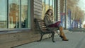 Young, beautiful, lovely woman sitting on bench in park, in hands of her notebook. She is wearing a coat. She makes Royalty Free Stock Photo