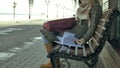 Young, beautiful, lovely woman sitting on bench in park, in hands of her notebook. She is wearing a coat. She makes Royalty Free Stock Photo