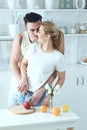 Young beautiful loving couple cutting fruits to make fresh juice and having fun in the kitchen at home Royalty Free Stock Photo