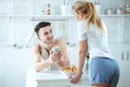 Young beautiful loving couple having breakfast and talking in the kitchen at home