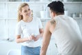 Young beautiful loving couple standing in the kitchen opposite each other and laughing while drinking coffee Royalty Free Stock Photo