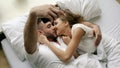 Young beautiful and loving couple take selfie picture on smartphone camera and kiss while lying in bed at the morning Royalty Free Stock Photo