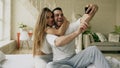 Young beautiful and loving couple take selfie picture on smartphone camera while sitting in bed at the morning Royalty Free Stock Photo