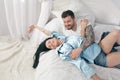 Young beautiful and loving couple take selfie picture on smartphone camera while sitting in bed at the morning Royalty Free Stock Photo