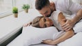 Young beautiful and loving couple wake up at the morning. Attractive man kiss and hug his wife in bed Royalty Free Stock Photo