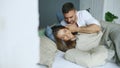 Young beautiful and loving couple wake up at the morning. Attractive man kiss and hug his wife in bed Royalty Free Stock Photo