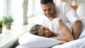 Young beautiful and loving couple wake up at the morning. Attractive man kiss and hug his wife in bed Royalty Free Stock Photo