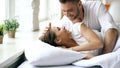 Young beautiful and loving couple wake up at the morning. Attractive man kiss and hug his wife in bed Royalty Free Stock Photo