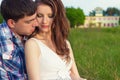 Young beautiful loving happy couple sitting in the box on the grass in the warm evening summer day Royalty Free Stock Photo