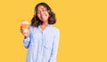 Young beautiful mixed race woman drinking a coffee from take away cup looking positive and happy standing and smiling with a Royalty Free Stock Photo