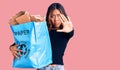 Young beautiful mixed race woman holding recycling wastebasket with paper and cardboard with open hand doing stop sign with Royalty Free Stock Photo