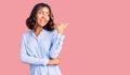 Young beautiful mixed race woman wearing casual business shirt smiling with happy face looking and pointing to the side with thumb Royalty Free Stock Photo