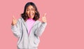 Young beautiful mixed race woman wearing casual sporty clothes success sign doing positive gesture with hand, thumbs up smiling Royalty Free Stock Photo