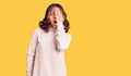 Young beautiful mixed race woman wearing winter turtleneck sweater yawning tired covering half face, eye and mouth with hand Royalty Free Stock Photo