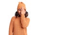 Young beautiful mixed race woman wearing wool sweater and winter hat covering one eye with hand, confident smile on face and Royalty Free Stock Photo