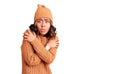 Young beautiful mixed race woman wearing wool sweater and winter hat shaking and freezing for winter cold with sad and shock Royalty Free Stock Photo