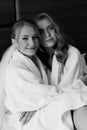 Young beautiful models sit on the bed in white coats. Black and white photo
