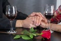 Couple hands on restaurant table with two glasses of red wine and roses Royalty Free Stock Photo