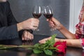 Man and female toasting with glasses of red wine on restaurant table with red rose flowers Royalty Free Stock Photo