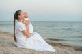 Young beautiful mom sitting on beach and hugging baby. Mothers love and care