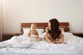 Young beautiful mom in sleepwear sitting on bed with her baby daughter smiling playing at home. Royalty Free Stock Photo